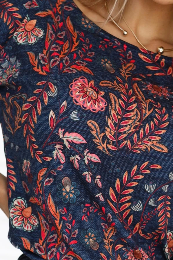 A vibrant dress featuring a rich floral pattern in shades of red, orange, and pink on a deep blue background. The design includes intricate leaves and flowers, creating a lively and eye-catching look.