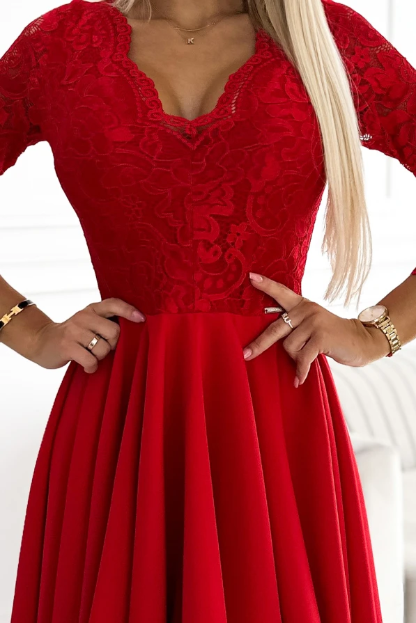 A red dress with a lace bodice and V-neckline, featuring short sleeves and a flowing, pleated skirt. The elegant design is complemented by intricate lace detailing on the upper part.