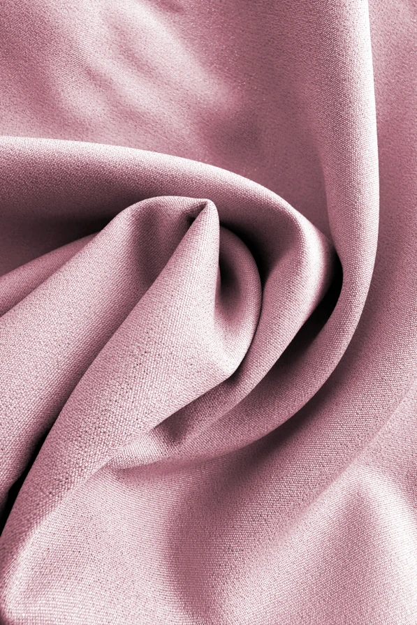 A close-up of a soft, pink fabric with a smooth texture and gentle folds. The material appears luxurious and elegant, ideal for creating stylish garments.