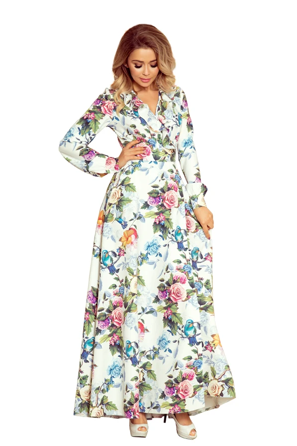 A long floral maxi dress with a ruffled hem, featuring a vibrant pattern of roses and butterflies on a light background. The dress has long sleeves and a V-neckline, creating an elegant and feminine silhouette.