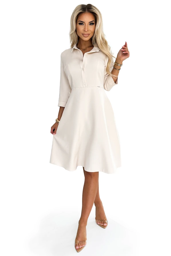 A stylish, cream-colored shirt dress with a flared skirt and three-quarter sleeves, perfect for both casual and formal occasions. The dress features a classic collar and button-down front, adding a touch of elegance to its modern design.