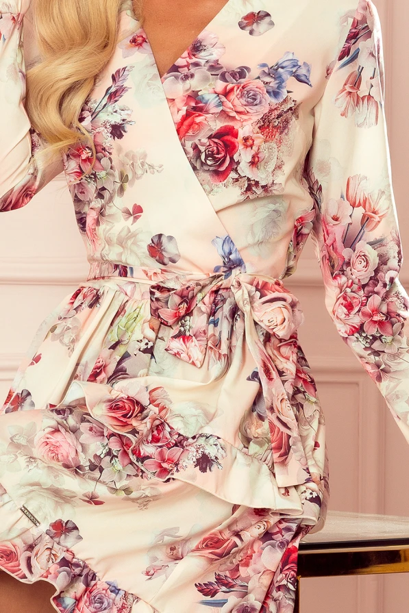 Elegant floral dress with a wrap design, featuring a delicate tie at the waist. The fabric showcases a vibrant array of pink and purple flowers, adding a touch of romance and sophistication.
