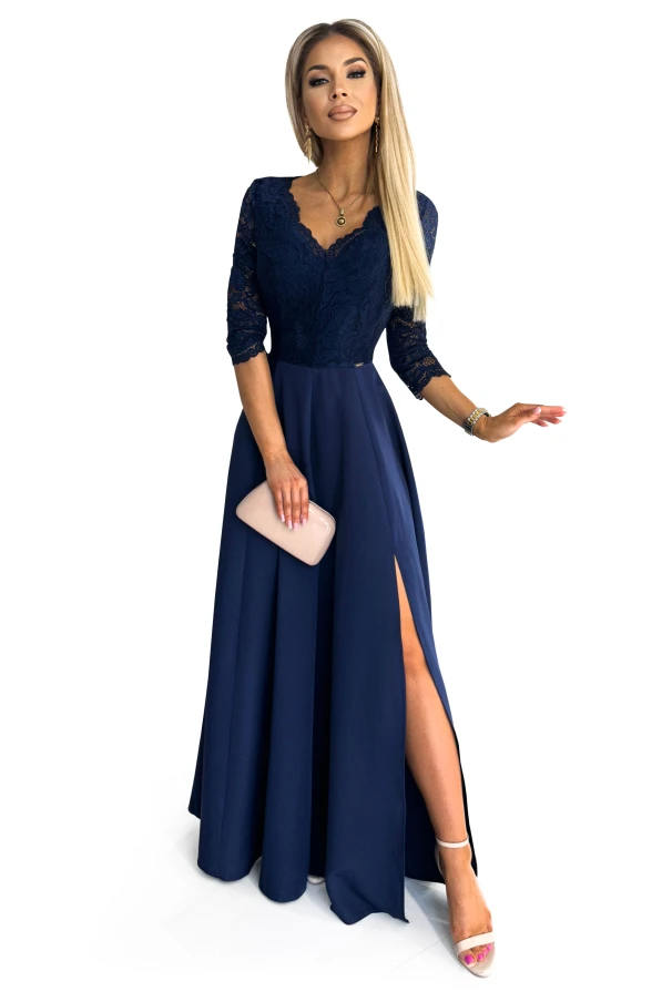 A navy blue evening gown with a lace bodice and three-quarter sleeves, featuring a deep V-neckline and a high slit on the skirt. The dress is elegantly paired with a nude clutch and strappy heels.