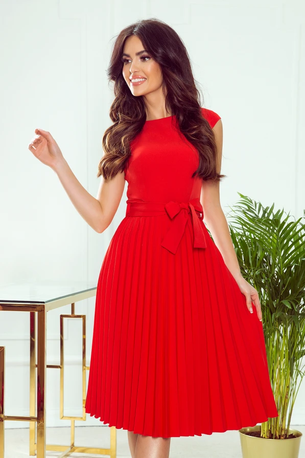 A vibrant red pleated dress with a fitted bodice and a matching waist tie, creating an elegant silhouette. The dress features cap sleeves and a flowing skirt, perfect for both casual and formal occasions.