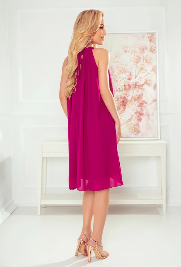 A woman is wearing a vibrant magenta chiffon dress that flows elegantly to just above the knees. The dress features a sleeveless design with a loose, airy fit, perfect for warm weather occasions.