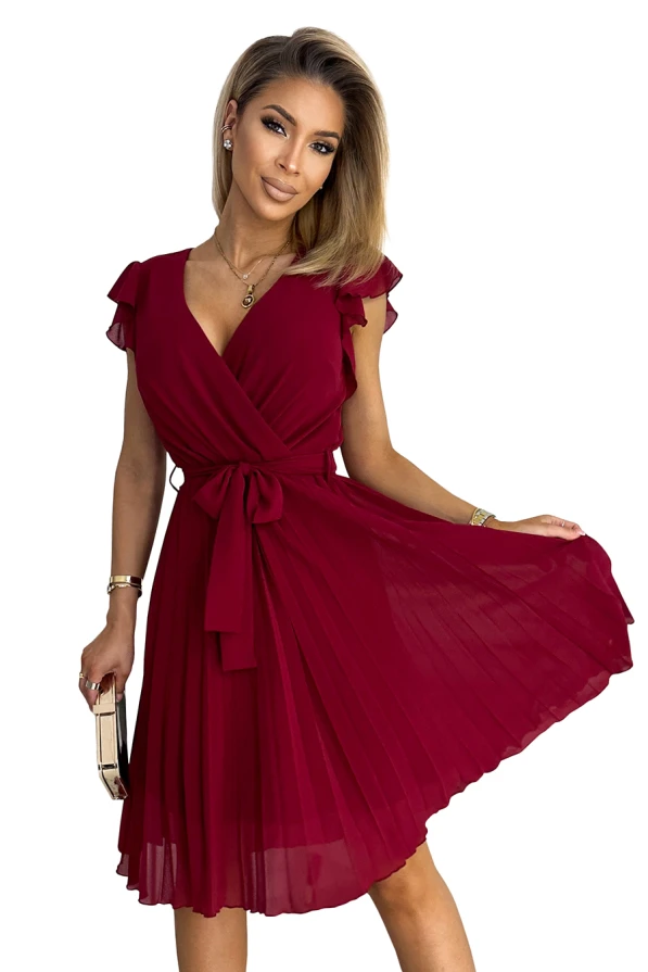 A pleated burgundy dress with a wrap-style bodice and flutter sleeves, tied at the waist with a matching sash. The dress features a knee-length hemline and a flowing, elegant silhouette.