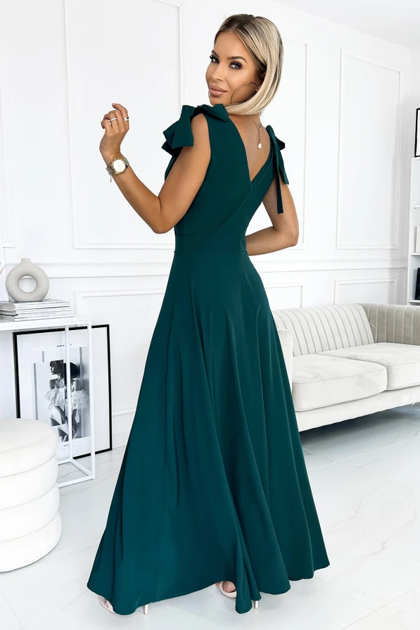 A long, elegant green dress with a fitted bodice and flowing skirt, featuring ruffled sleeves and a V-neckline tied with a bow at the back. The dress exudes sophistication, perfect for formal occasions or evening events.
