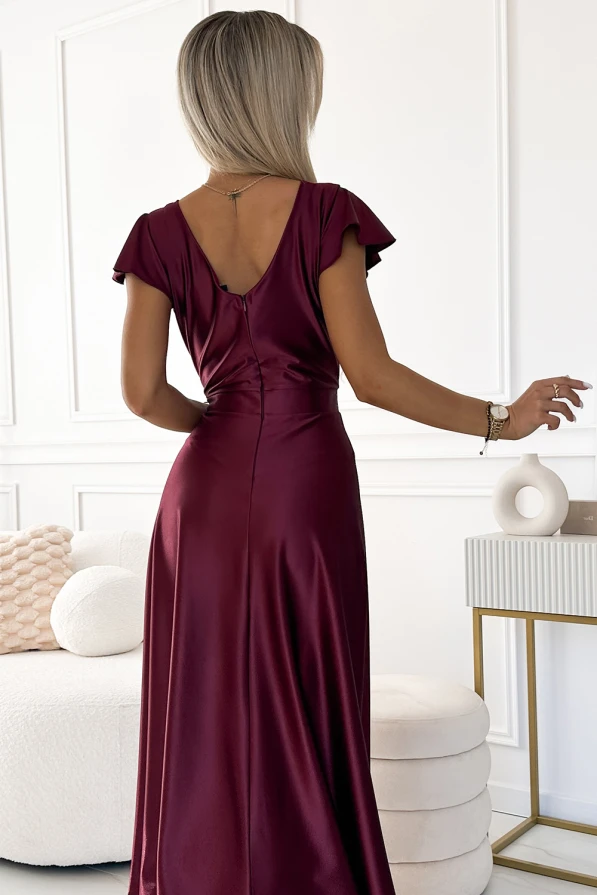A long, satin dress in a deep burgundy color features a fitted waist and a flowing skirt, creating an elegant silhouette. The dress has short, flutter sleeves and a V-shaped back, adding a touch of sophistication.