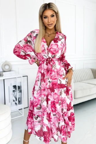 A woman is wearing a vibrant midi dress adorned with a bold floral pattern in shades of pink and white. The dress features a V-neckline and a cinched waist, creating an elegant and feminine silhouette.}