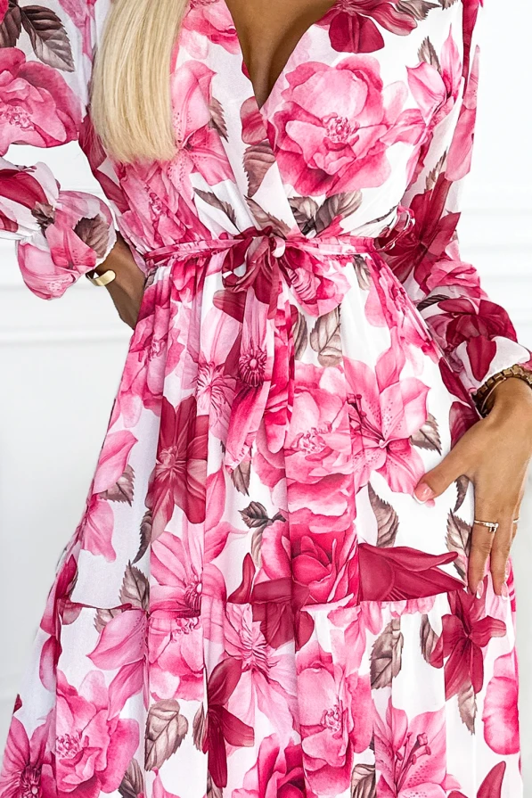 A floral midi dress featuring a vibrant pink and white pattern with large blossoms and subtle brown leaves. The dress has a wrap-style top with a tied waist, creating an elegant and feminine silhouette.
