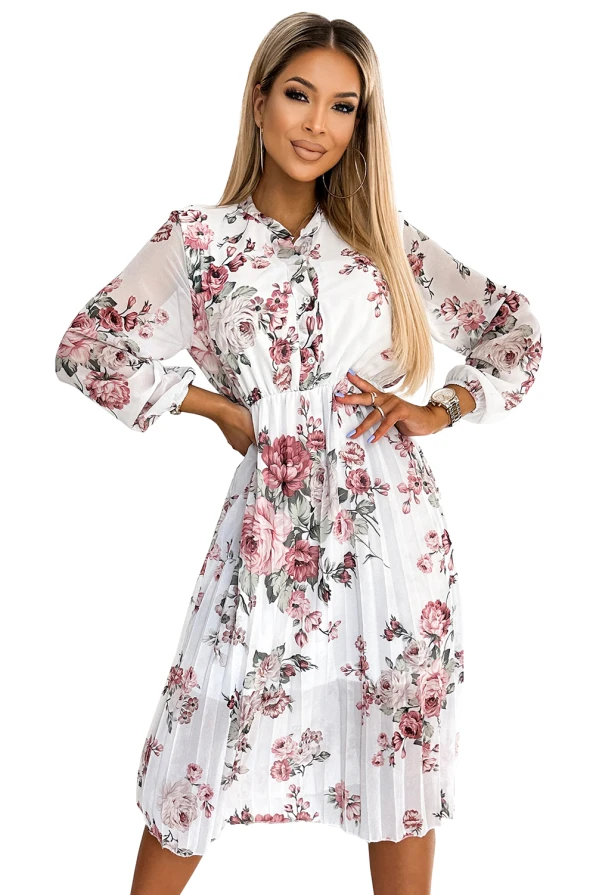 The image shows a knee-length, pleated dress with a floral pattern in shades of pink and white. The dress features long, sheer sleeves and a fitted waist, creating an elegant and feminine silhouette.