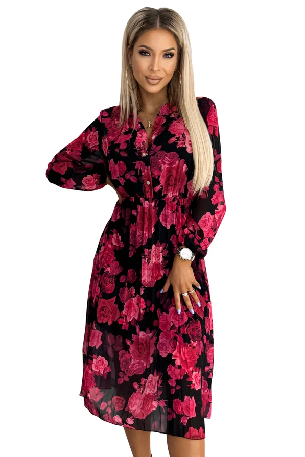 A pleated dress featuring a vibrant floral pattern with bold pink roses on a black background. The dress has long sleeves and a fitted waist, offering an elegant and feminine silhouette.