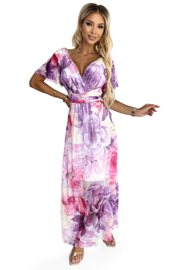 A floral maxi dress with a deep V-neckline and flutter sleeves, featuring a vibrant pattern of pink and purple flowers. The dress is cinched at the waist, creating a flattering silhouette perfect for spring and summer occasions.