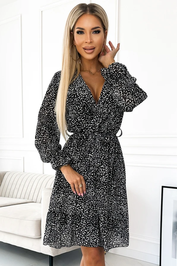 A chic chiffon dress featuring a delicate black and white pattern, perfect for both casual and formal occasions. The dress has long sleeves and a flattering waist tie, adding elegance and style.