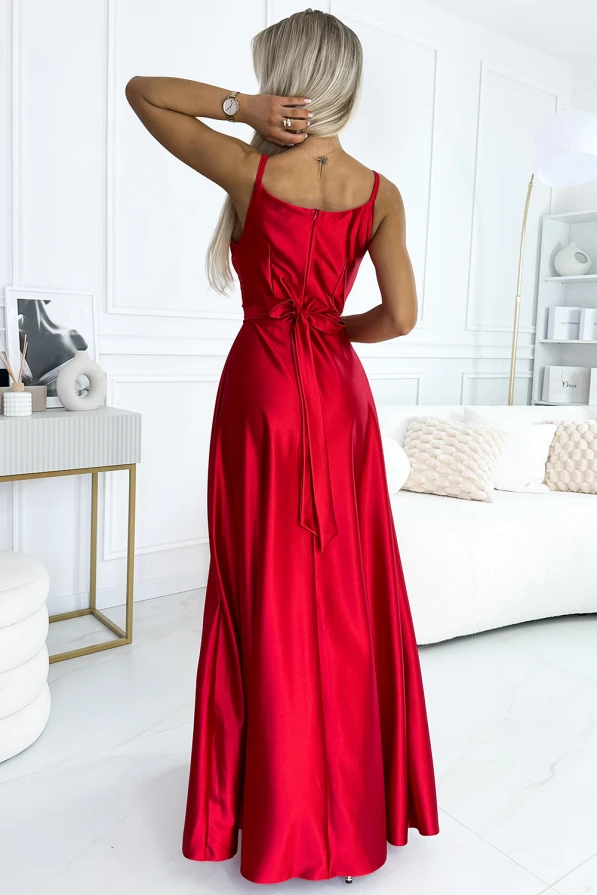A long, elegant red dress with a fitted bodice and a flowing skirt, featuring a bow detail at the back. The dress is made from a shiny fabric that adds a touch of sophistication, perfect for formal occasions.