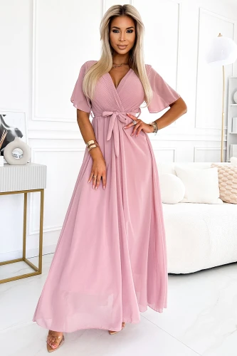A long, elegant dress in a soft pink hue features delicate pleats and a flattering wrap design with a tie at the waist. The dress has short, sheer sleeves and flows gracefully to the floor, perfect for formal occasions.}